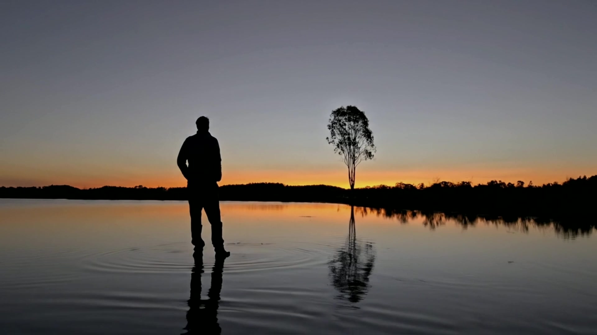 Mike Karame standing beside still water at sunset